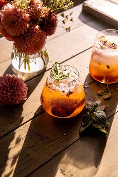 two glasses filled with drinks sitting on top of a wooden table