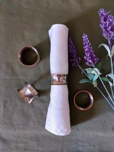 two napkin rings, one ring and the other on top of a table with purple flowers