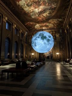 people sitting on benches in an ornate room with a large blue moon