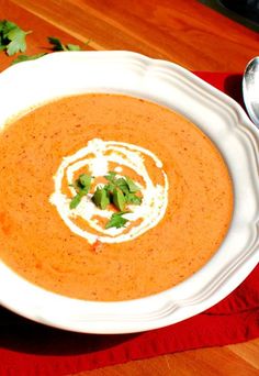 a white bowl filled with soup on top of a red cloth next to a spoon