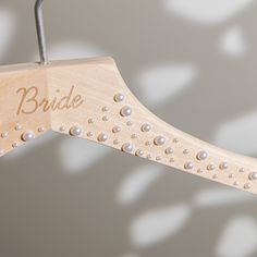 a wooden bridal hanger with pearls and the word bride on it's side