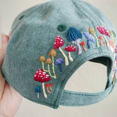 someone is holding up a baseball cap with embroidered mushrooms on it