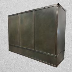 a metal box mounted to the side of a white wall with no one around it