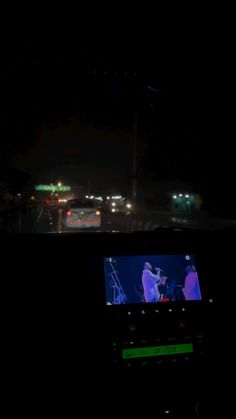 the dashboard of a car at night with lights in the background and cars driving down the road