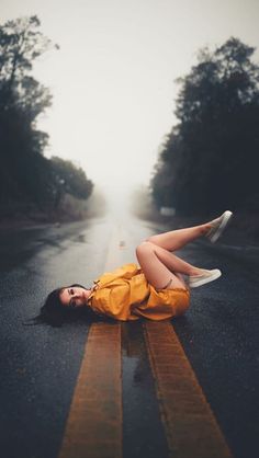 a woman laying on the road with her legs spread out and head in the air