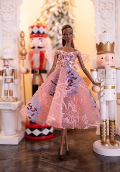 a barbie doll in a pink dress standing next to nutcrackers