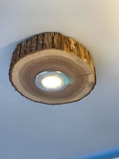 a ceiling light made out of wood with a circular hole in the center and a white wall behind it