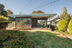 a small house in the middle of some bushes and trees with a blue roof on it