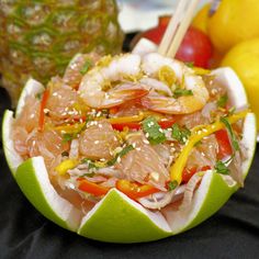 a fruit bowl filled with meat and veggies next to pineapples on a table