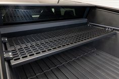 the inside of an open car trunk with metal grates in place to hold items