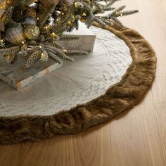 a christmas tree skirt is on the floor next to a small box with presents under it