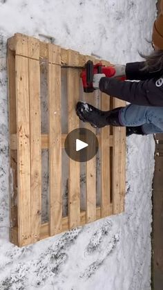 a woman is using a drill to build a pallet box in the snow with her hands