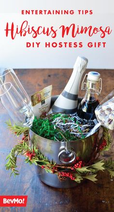 a metal pot filled with christmas items on top of a wooden table next to a bottle of wine