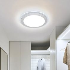 a white bathroom with a round light above the sink