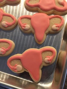 some cookies with pink icing are on a cookie sheet