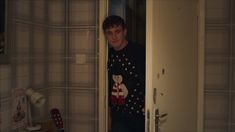 a young man standing in front of a door with a cat on his t - shirt