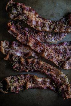 four pieces of meat sitting on top of a pan covered in herbs and seasoning