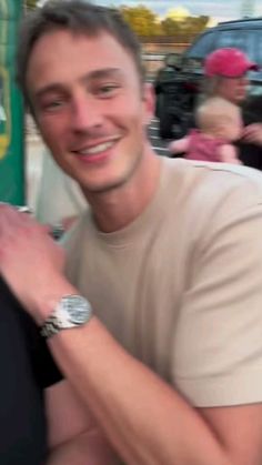 a man is smiling while holding onto his watch