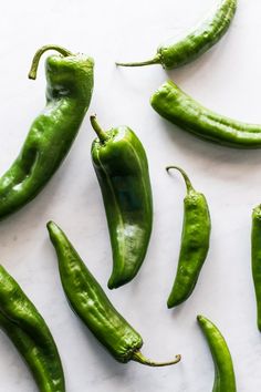 several green peppers on a white surface