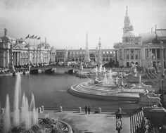 an old black and white photo of a fountain in the middle of a city square