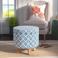 a blue and white foot stool sitting on top of a rug next to a chair