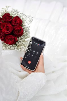 a person holding a cell phone in their left hand and a bouquet of roses in the other