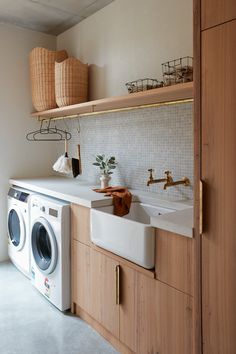 a washer and dryer in a small room with wooden shelves on the wall