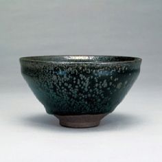 a black bowl sitting on top of a white table next to a cup with dots