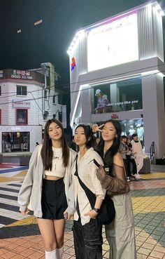 three young women standing next to each other in front of a building