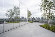 an empty parking lot with trees and buildings in the backgrounnd, as seen through large mirrors