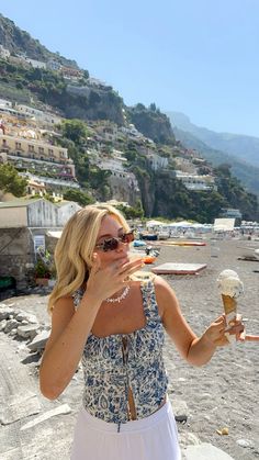 a woman eating an ice cream cone on the beach