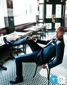 a man in a suit sitting on a chair with his legs crossed and feet up