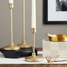 candles and other items on a table in front of a framed photograph with a gold candle holder