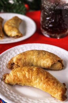 two white plates topped with pastries on top of a red tablecloth covered table