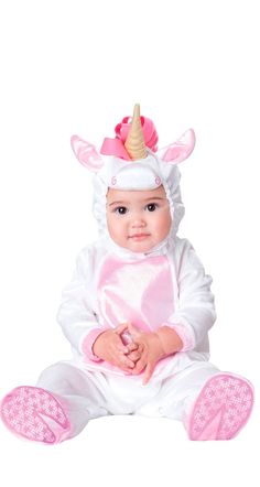 a baby in a unicorn costume sitting on the floor wearing a pink and white outfit