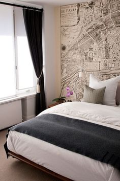 a bedroom with a large map on the wall above the bed and window behind it