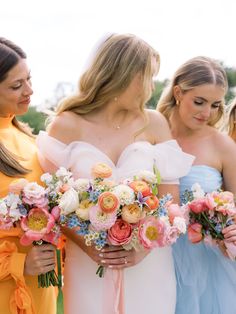 three bridesmaids holding bouquets of flowers in their hands and looking at each other