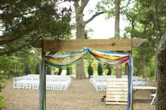 an outdoor wedding venue with white chairs and colorful ribbons