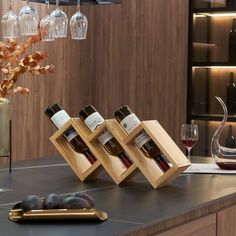 three bottles of wine in wooden boxes on a counter next to a vase with flowers