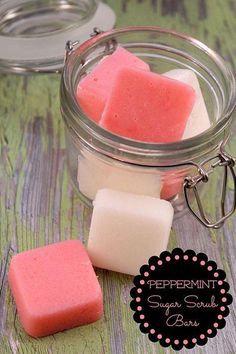 some pink and white soaps in a glass jar on a wooden table with the words peppermint sugar scrub