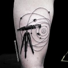 a man's leg with a tattoo on it that has an image of a telescope in the center