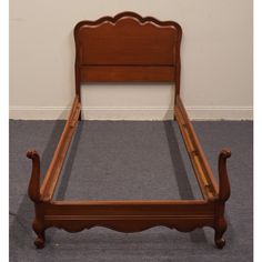 a wooden bed frame sitting on top of a carpeted floor next to a wall