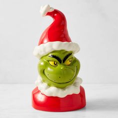 the grin face is wearing a red santa claus hat and green eyes are featured in this ceramic christmas ornament