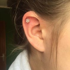 a woman with a tiny flower tattoo on her left ear