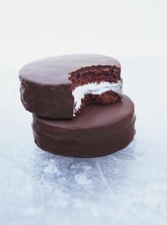 two pieces of chocolate cake sitting on top of each other in the middle of snow