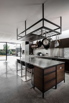 an open kitchen with stainless steel counter tops and hanging pots