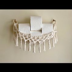 three rolls of toilet paper are hanging on the wall with tassels attached to them