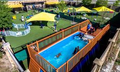 an aerial view of a swimming pool with people in it and yellow umbrellas on the roof