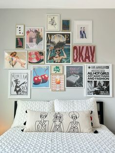 a white bed topped with lots of pictures on the wall