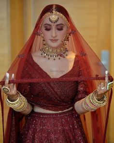 a woman wearing a red bridal outfit and jewelry